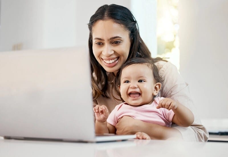 A mother and baby using telehealth on a laptop